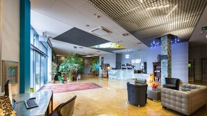 A spacious lobby with a reception desk, seating area, and a large plant. - Hotel Lenart (Wieliczka)