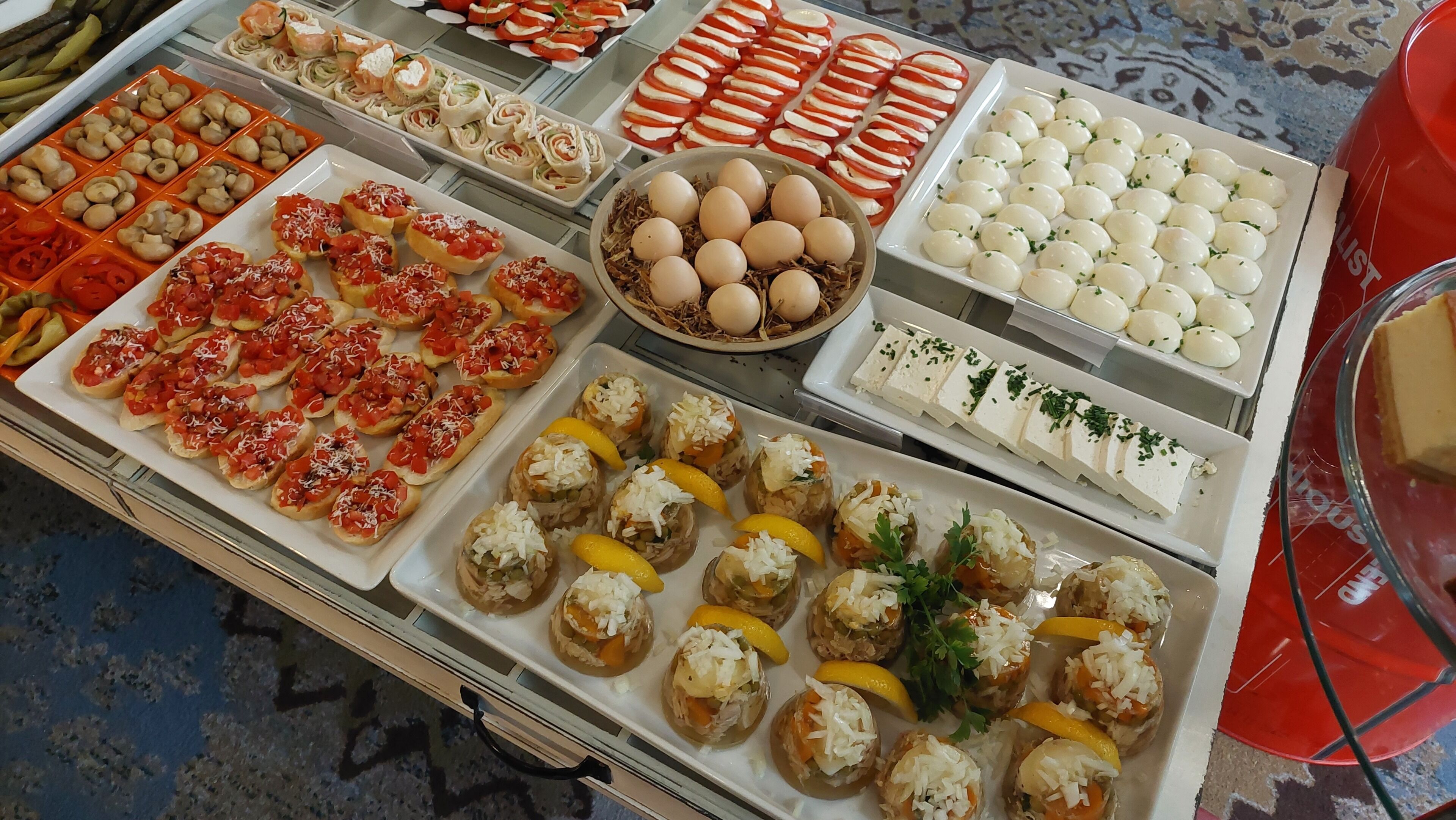 A buffet with various food items including bread with tomato, cheese, and other toppings, as well as eggs and possibly some salads.