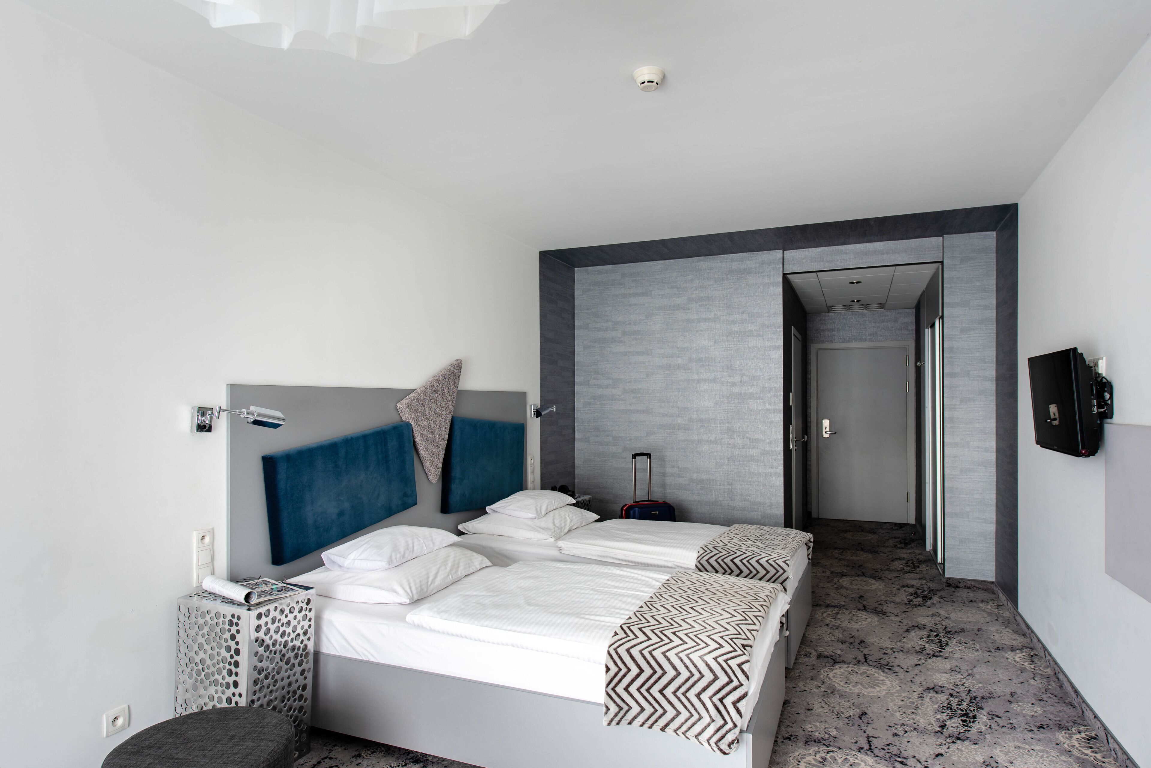 Una camera d'albergo moderna con un letto grande, un armadio, una scrivania e una cabina armadio.