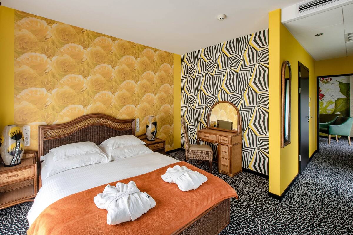 A hotel room with a bed, a desk, a chair, and a mirror.