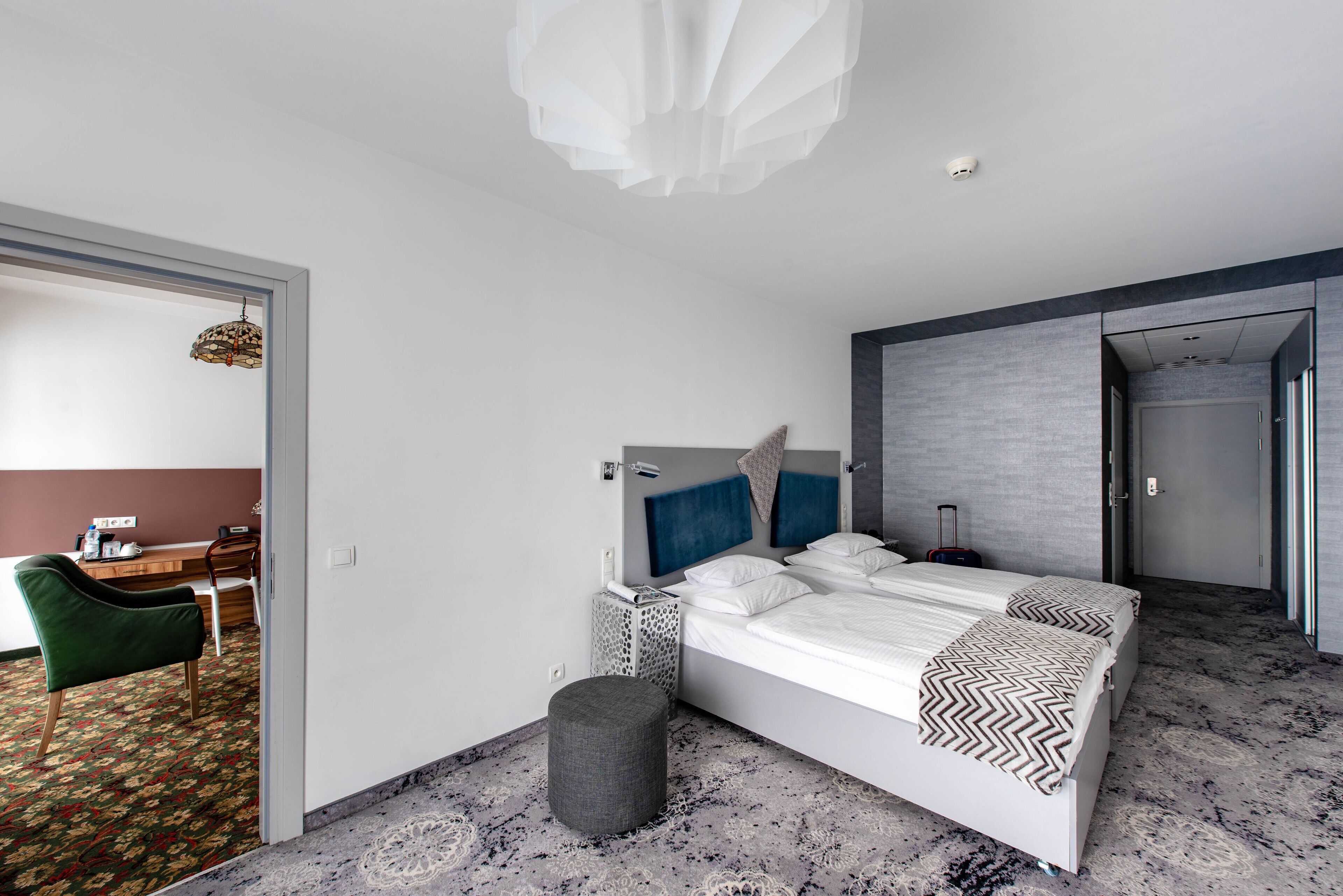 A modern hotel room with a large bed, a desk, and a chair.