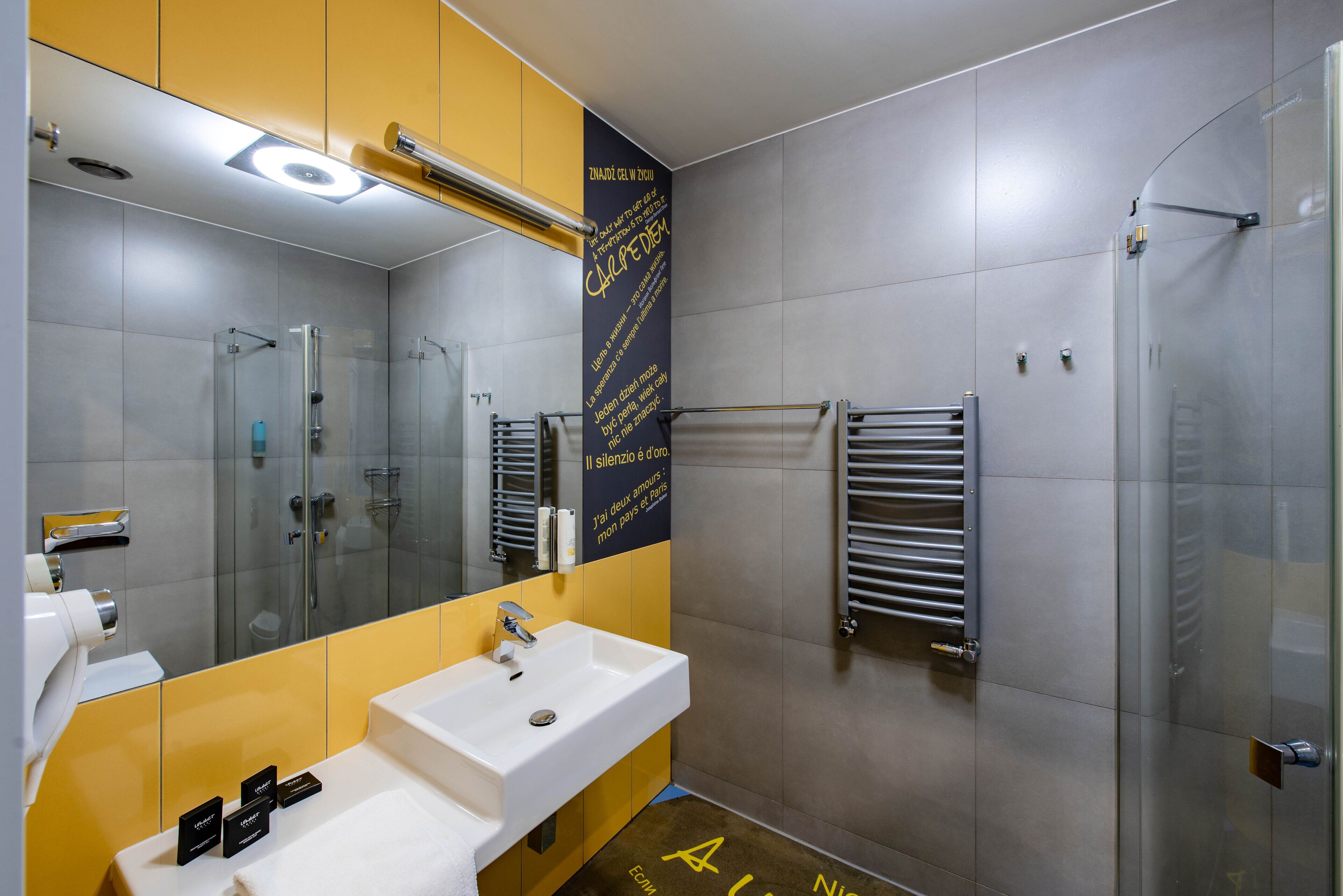 Un baño moderno con un lavamanos blanco, cabina de ducha con paredes de vidrio y un perchero para toallas.