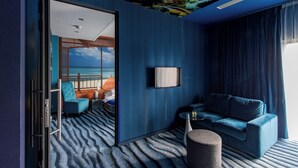 A modern room with a view of the ocean, a blue sofa, a small table, and a unique ceiling mural. - Hotel Lenart (Wieliczka)