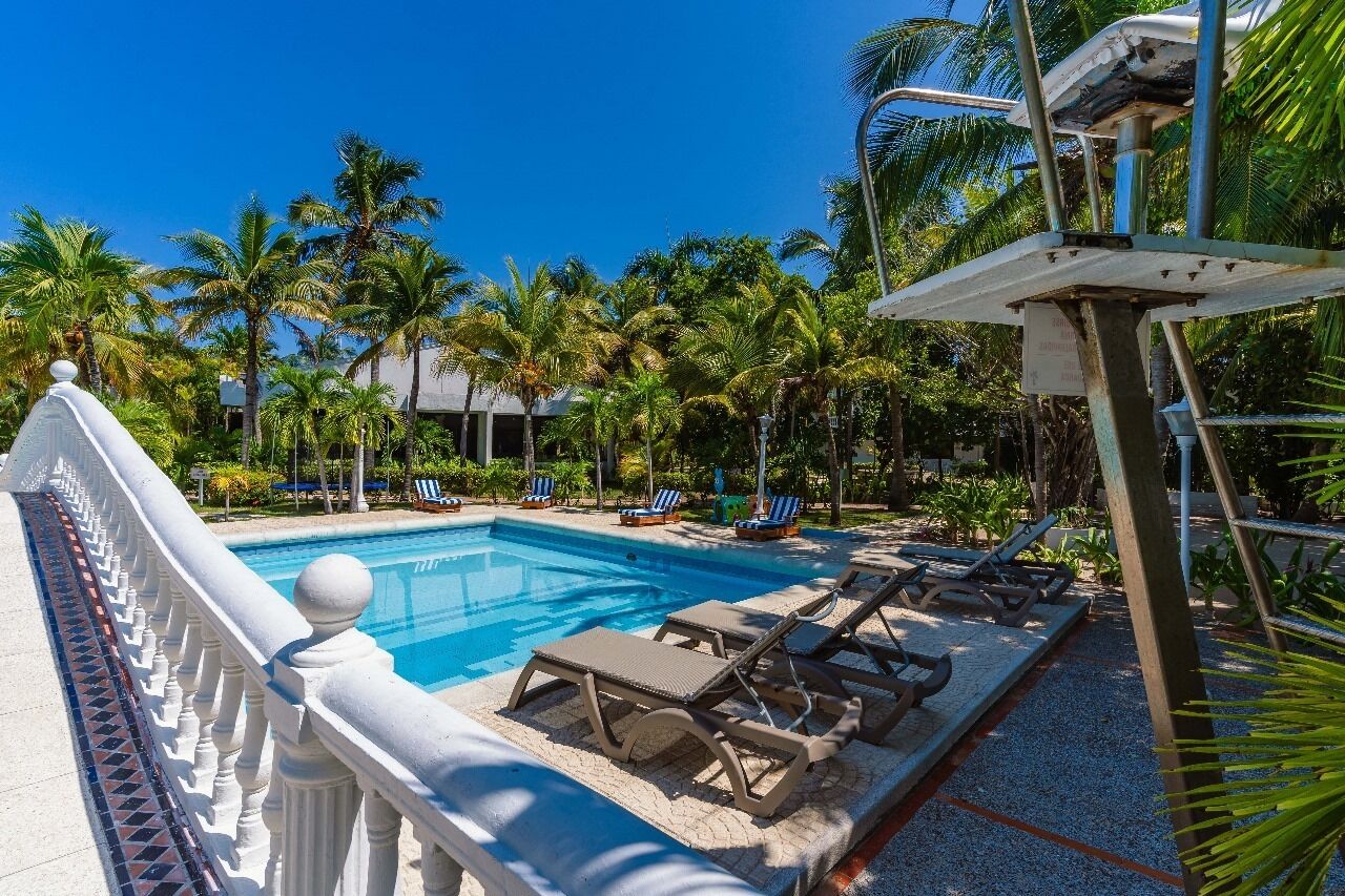 A swimming pool with lounge chairs and palm trees in the background.