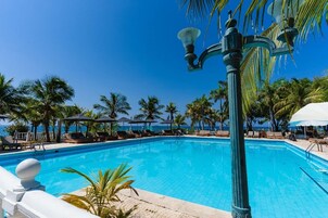 Una piscina al aire libre, sombrillas, sillones reclinables de piscina