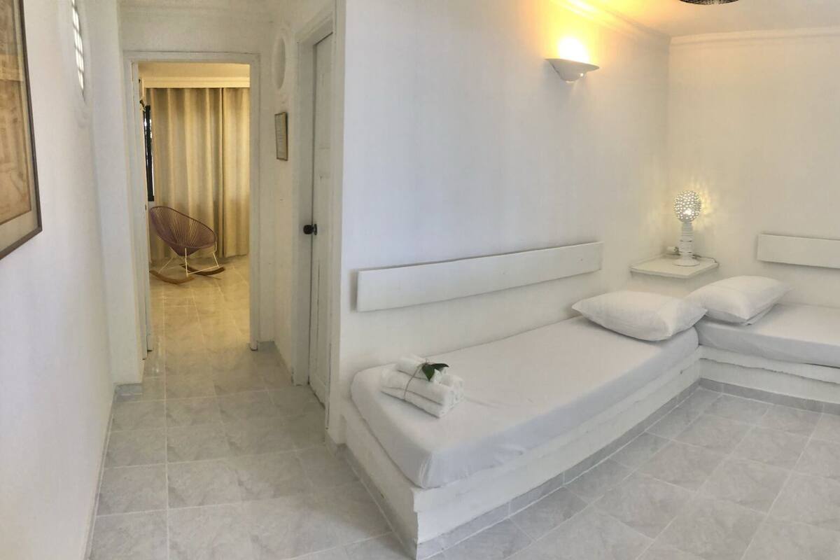 A modern bedroom with a curved bed, a bedside lamp, and a view of the hallway.
