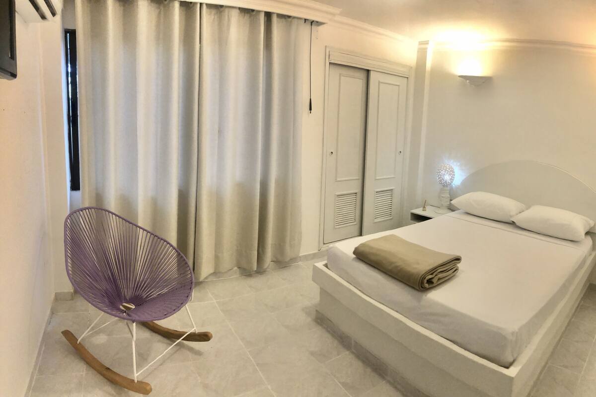 A bedroom with a bed, a chair, a nightstand, and a wardrobe.