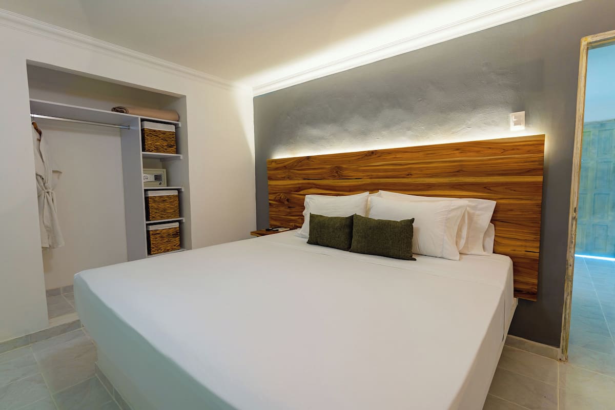 A bedroom with a large bed, wooden headboard, built-in shelving, and a walk-in closet.