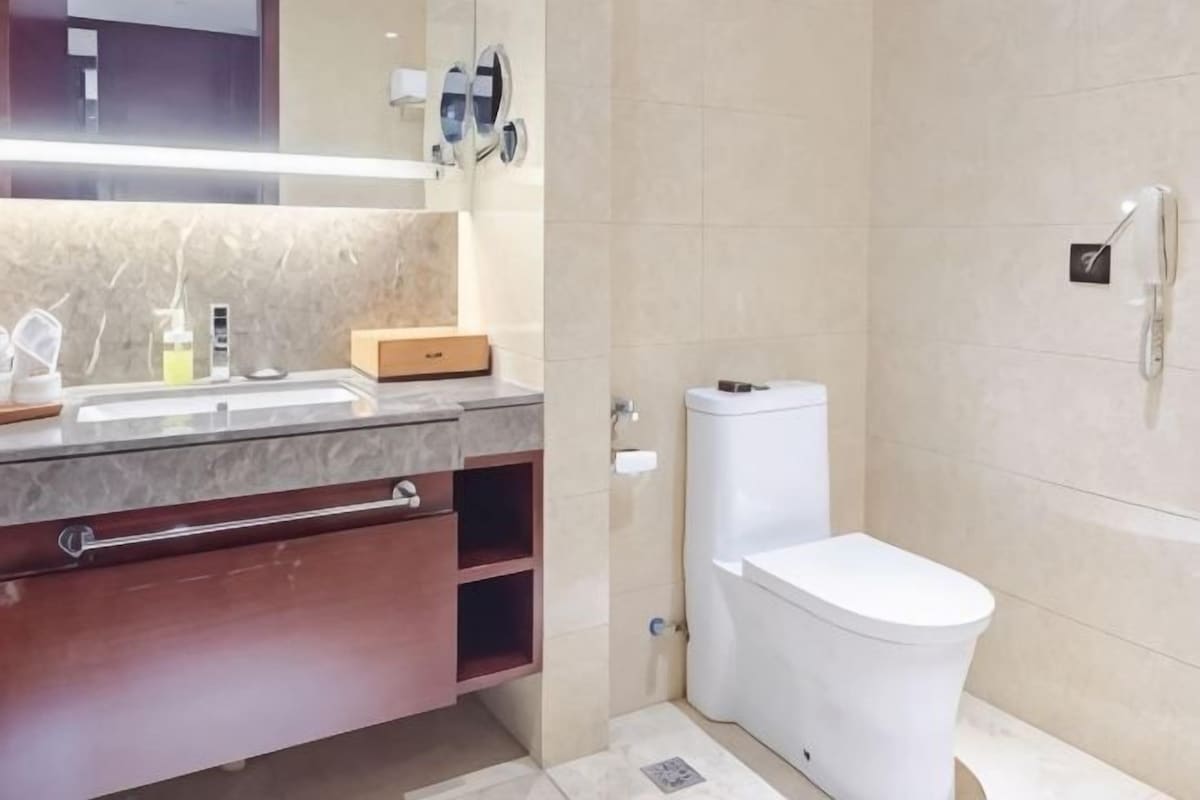 Un baño moderno con encimera de mármol, inodoro y zona de ducha.