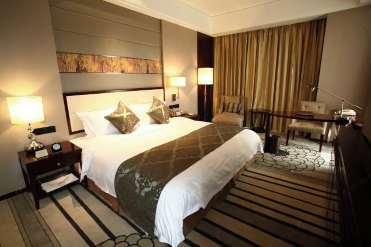 A hotel room with a large bed, two bedside tables, a desk, and a chair.