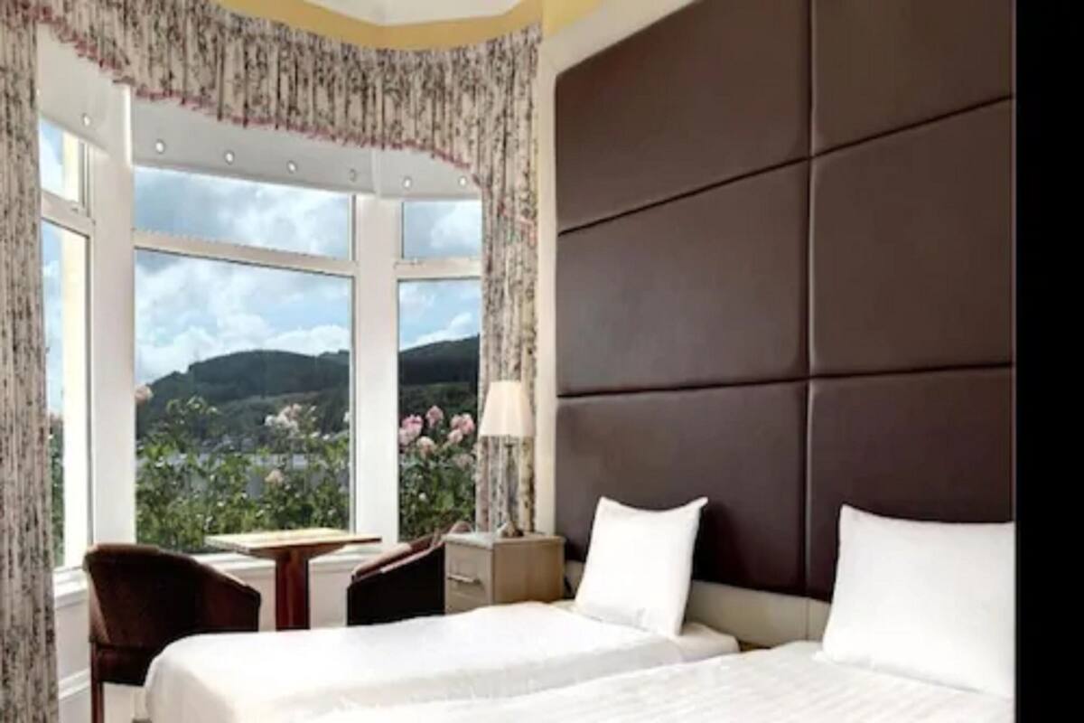 A hotel room with a large bed, a desk, and a view of the outdoors.
