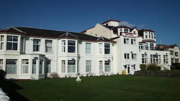 A white building with a sign that reads "Hotel Planade." It has multiple windows and a red roof.