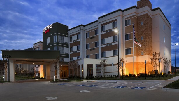 Un hôtel Courtyard by Marriott au design moderne, avec plusieurs étages et une entrée bien éclairée.
