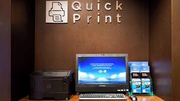 A desk with a printer, a laptop, and a keyboard.