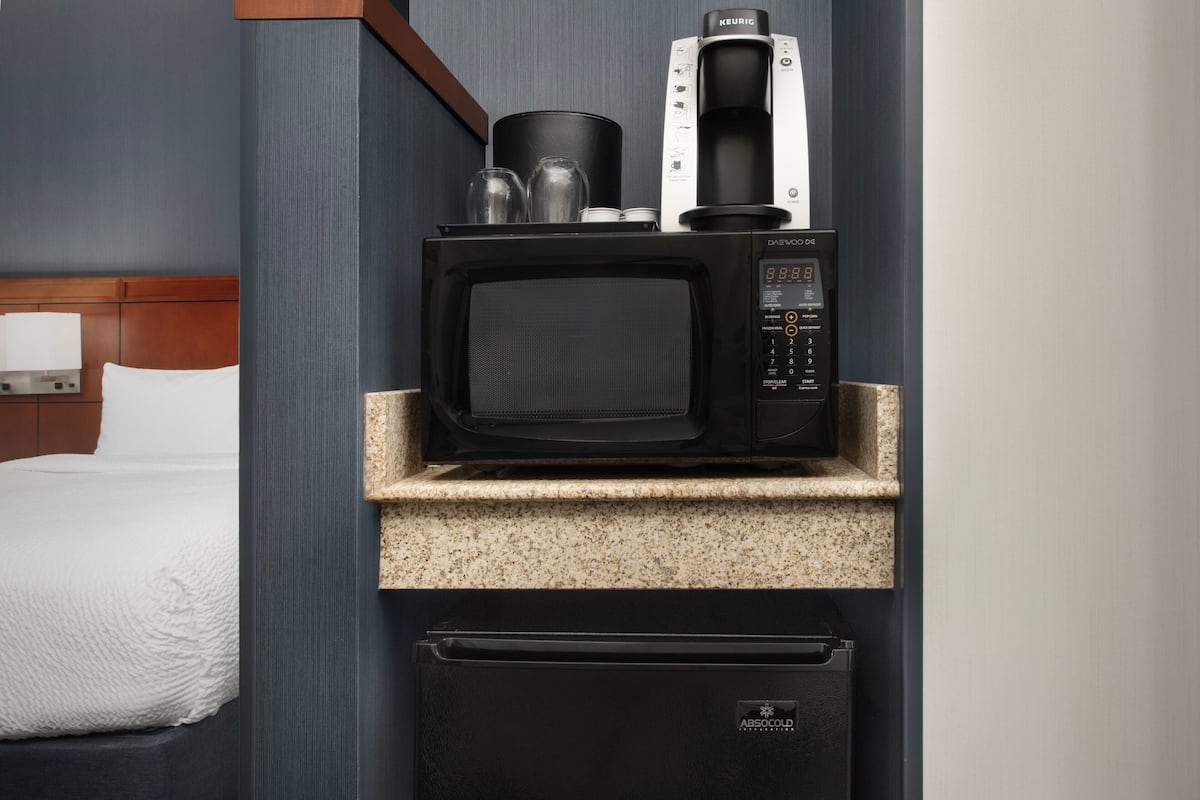 Eine kleine Küchenzeile mit Mikrowelle, Kaffeemaschine und Kühlschrank.