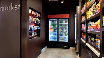 A corridor with a refrigerated display case and shelves stocked with snacks.