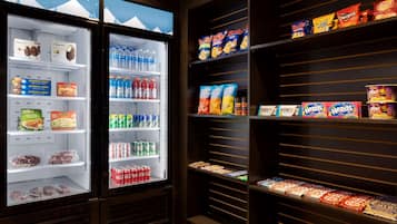 Un présentoir réfrigéré contenant divers en-cas et boissons, notamment des chips Doritos, des sodas et du chocolat Hershey's.