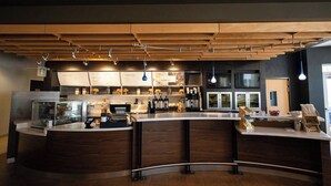 A modern bar area with a curved counter, wooden ceiling, and pendant lighting.