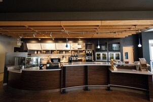 Un área de bar moderna con barra curva, techo de madera e iluminación colgante.