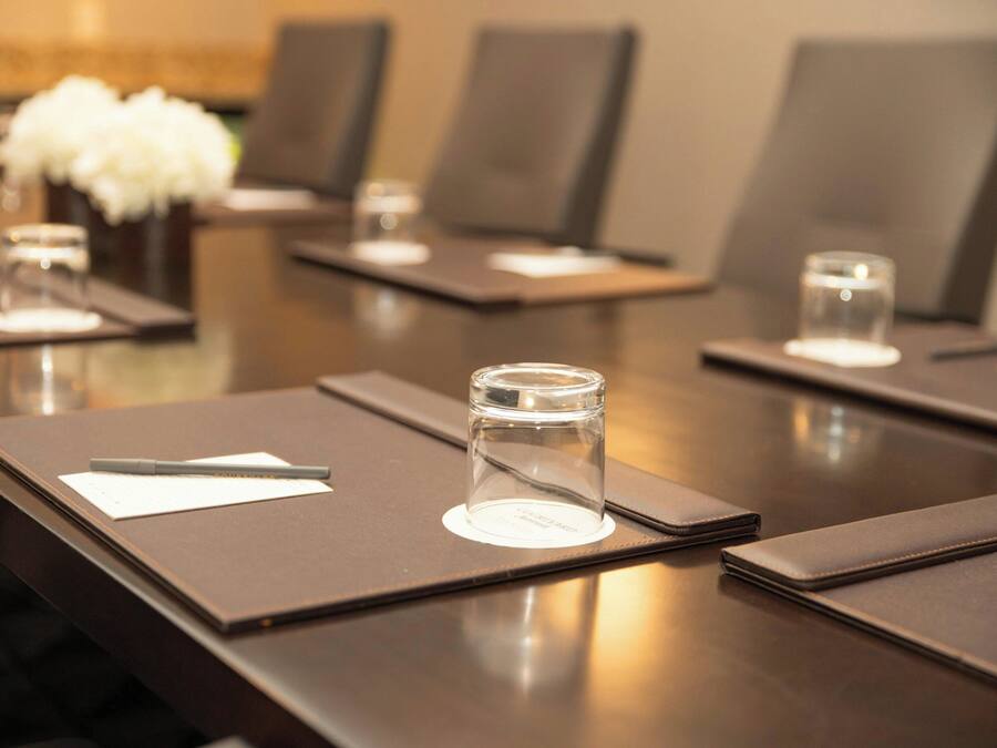 A conference room with tables set for meetings, each with a notepad, pen, and a glass of water.