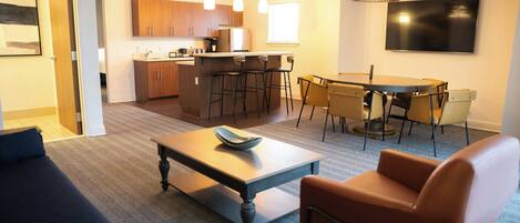 A modern living room with a sofa, a coffee table, and a dining area with a table and chairs.