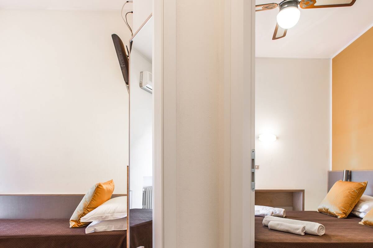 A hotel room with two beds, a ceiling fan, and a mirror.