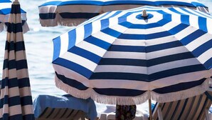 A beach scene with striped umbrellas and lounge chairs. - Hotel Antares (Cervia)