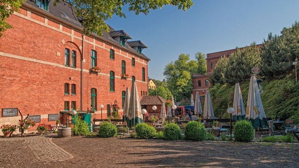 Ein rotes Backsteinhaus mit Innenhof, Außenbereich und Sonnenschirmen.