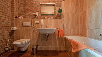 A bathroom with a brick wall, a sink, a toilet, and a bathtub.