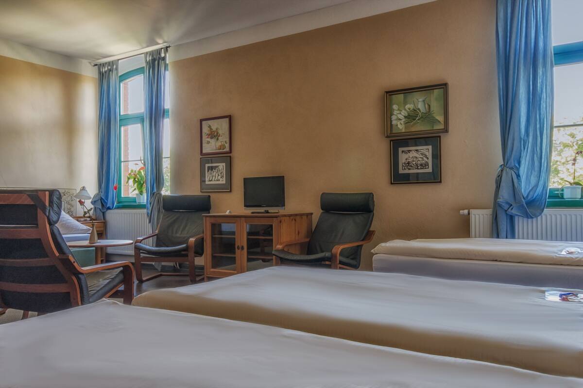 Une chambre d’hôtel avec deux lits, un bureau avec un ordinateur, une chaise et une fenêtre avec des rideaux.
