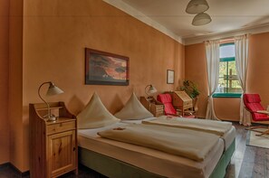 Hotelkamer met twee bedden, een nachtkastje, een bureau, een stoel en een raam met gordijnen.