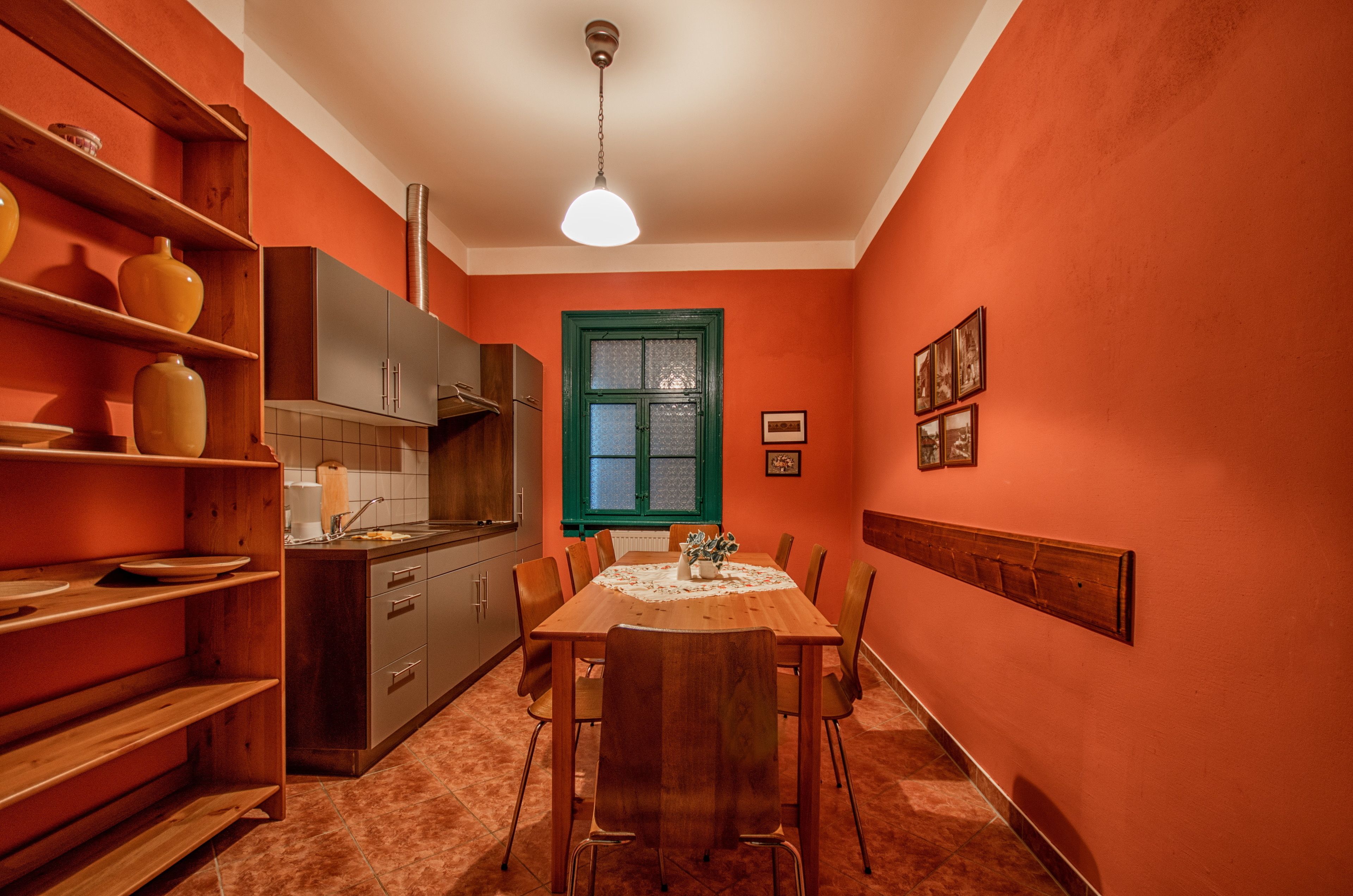 A kitchen with a dining table, wooden cabinets, and a window with green trim.