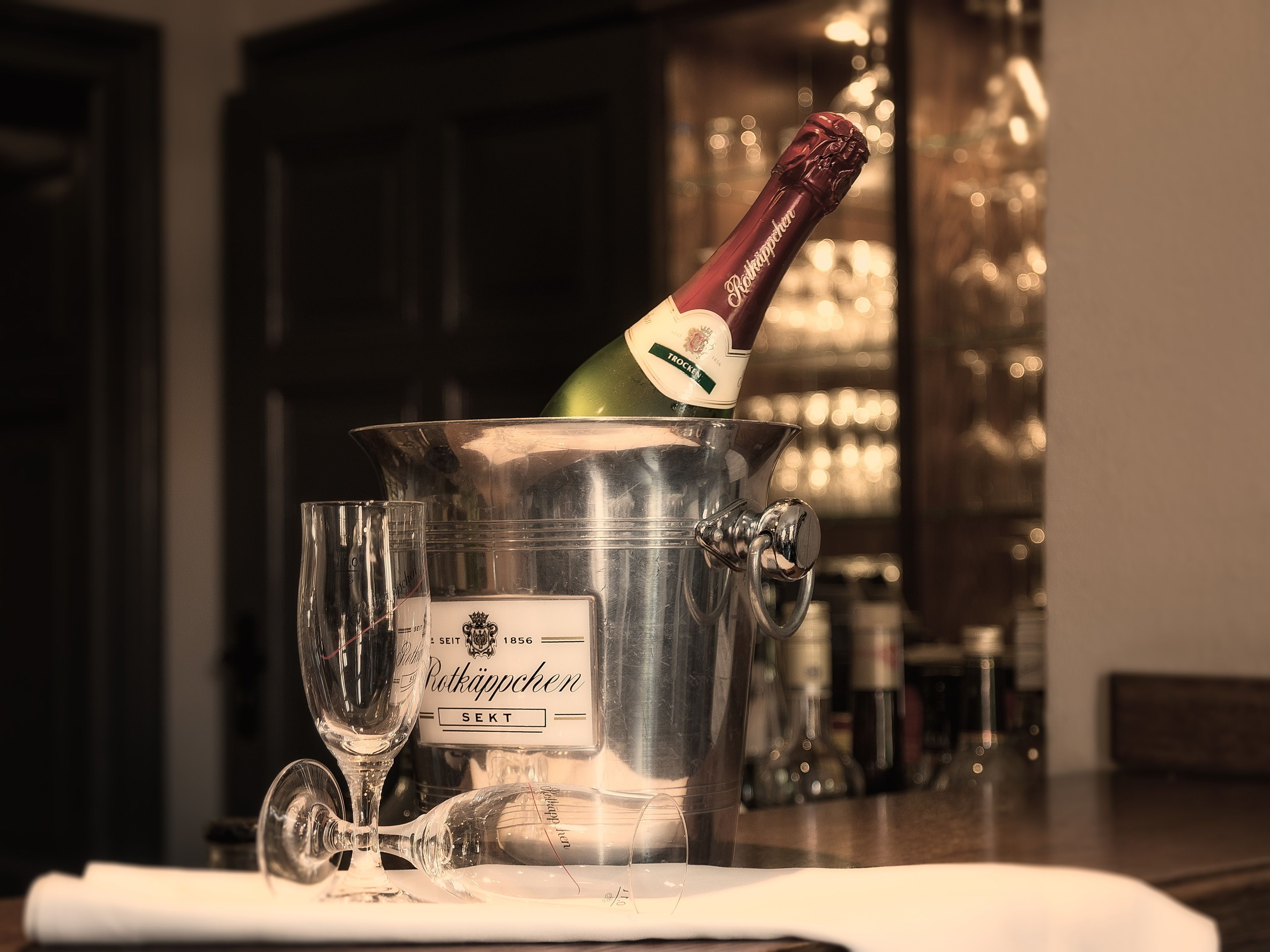 Eine Flasche Rothäppchen Champagner in einem Eiskübel mit zwei leeren Gläsern daneben.