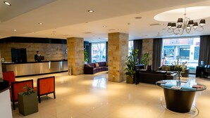 A modern hotel lobby with a reception desk, seating area, and a central coffee table. - Neuquen Tower Hotel (Neuquén)