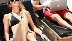 Two people lounging by a poolside with a laptop. - Neuquen Tower Hotel (Neuquén)