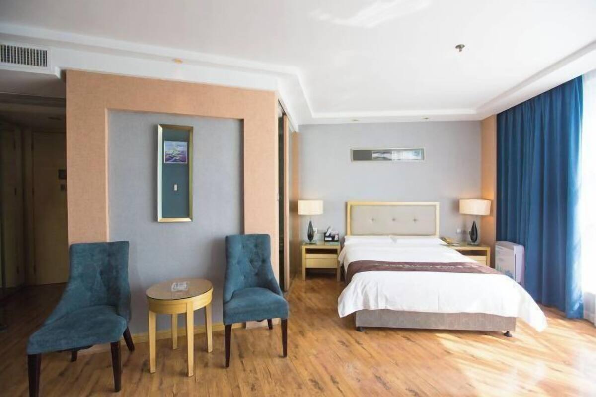 Ein Hotelzimmer mit einem Bett, zwei Stühlen, einem kleinen Tisch und einem Nachttisch.