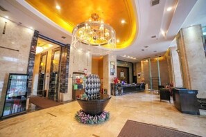 A lobby with a large chandelier, a reception desk, and a decorative centerpiece. - Hechi Shang Pin Hotel (Xiangyang)