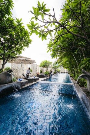 A swimming pool with lounge chairs and a person tending to the water.