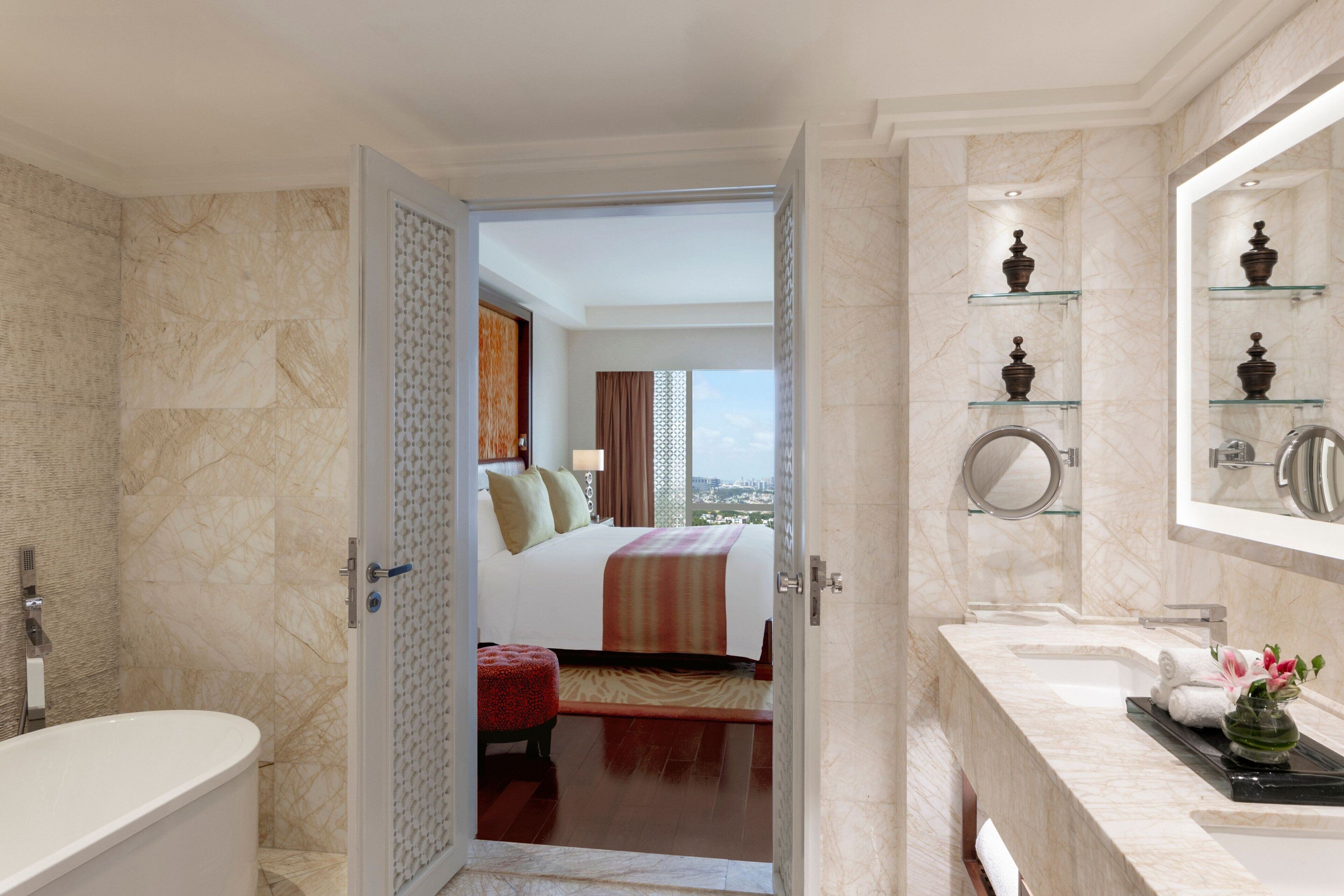 Una habitación de hotel con baño, cama con vistas y tocador con espejo.