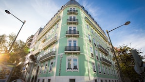 A multi-story building with balconies, a sign indicating it is a hotel, and a clear sky.