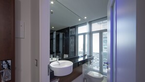 A modern bathroom with a large mirror, a white sink, and a toilet.
