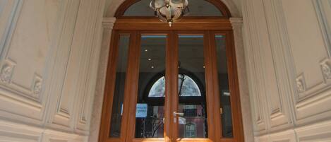 A grand entrance with a wooden door, a staircase leading up, and a decorative ceiling.