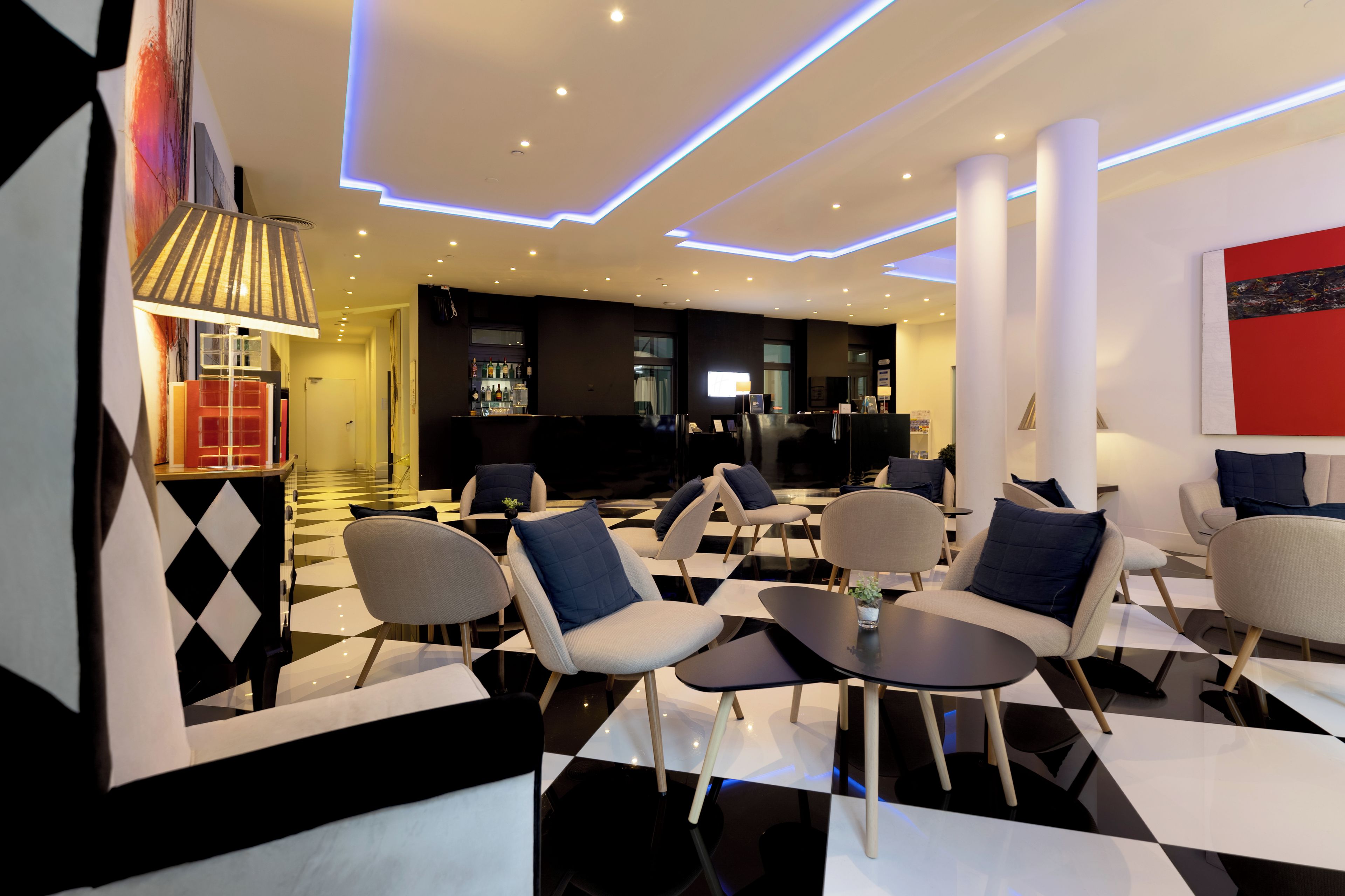 A modern lounge area with checkered flooring, contemporary furniture, and ambient lighting.