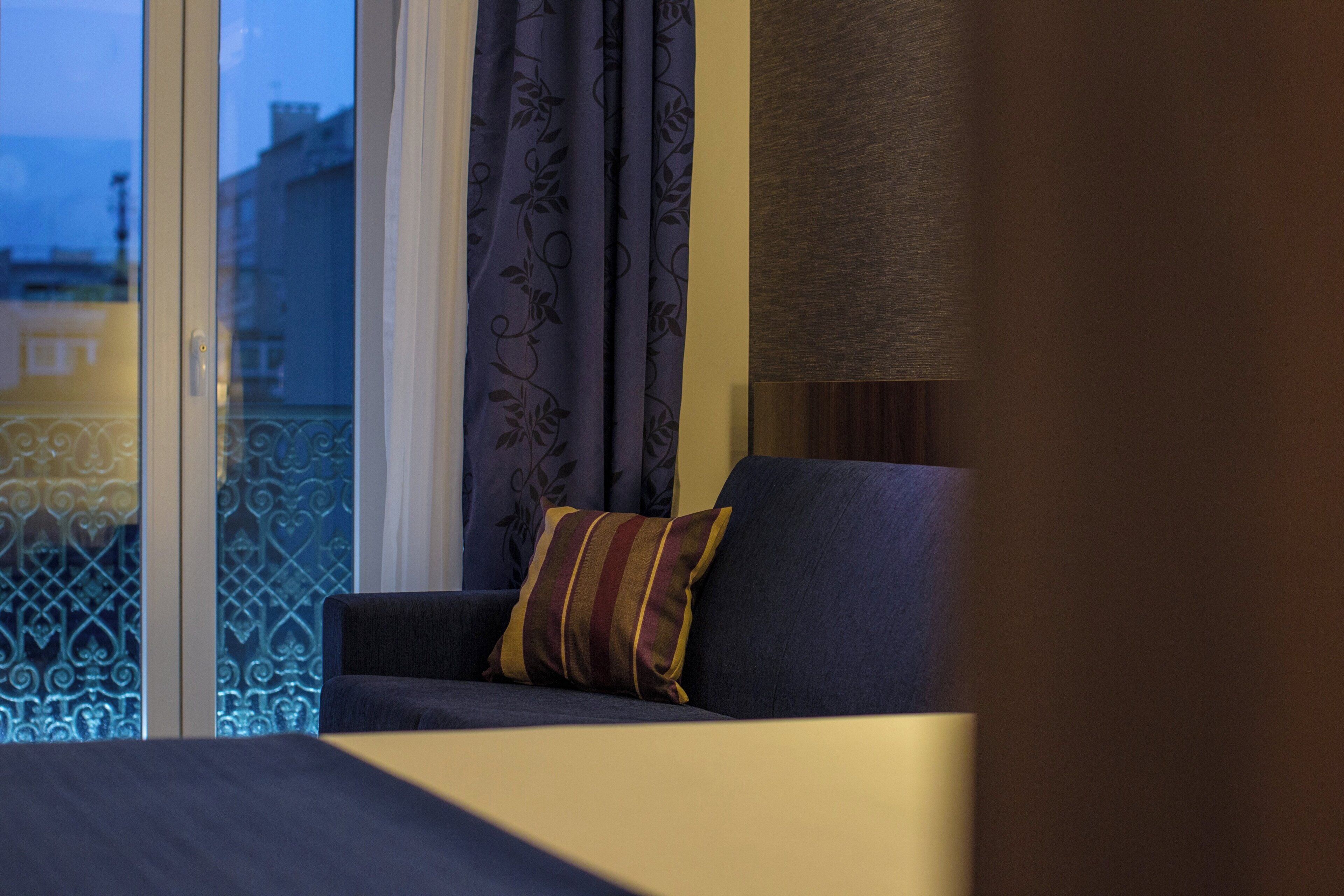 A room with a sofa and a window with curtains.