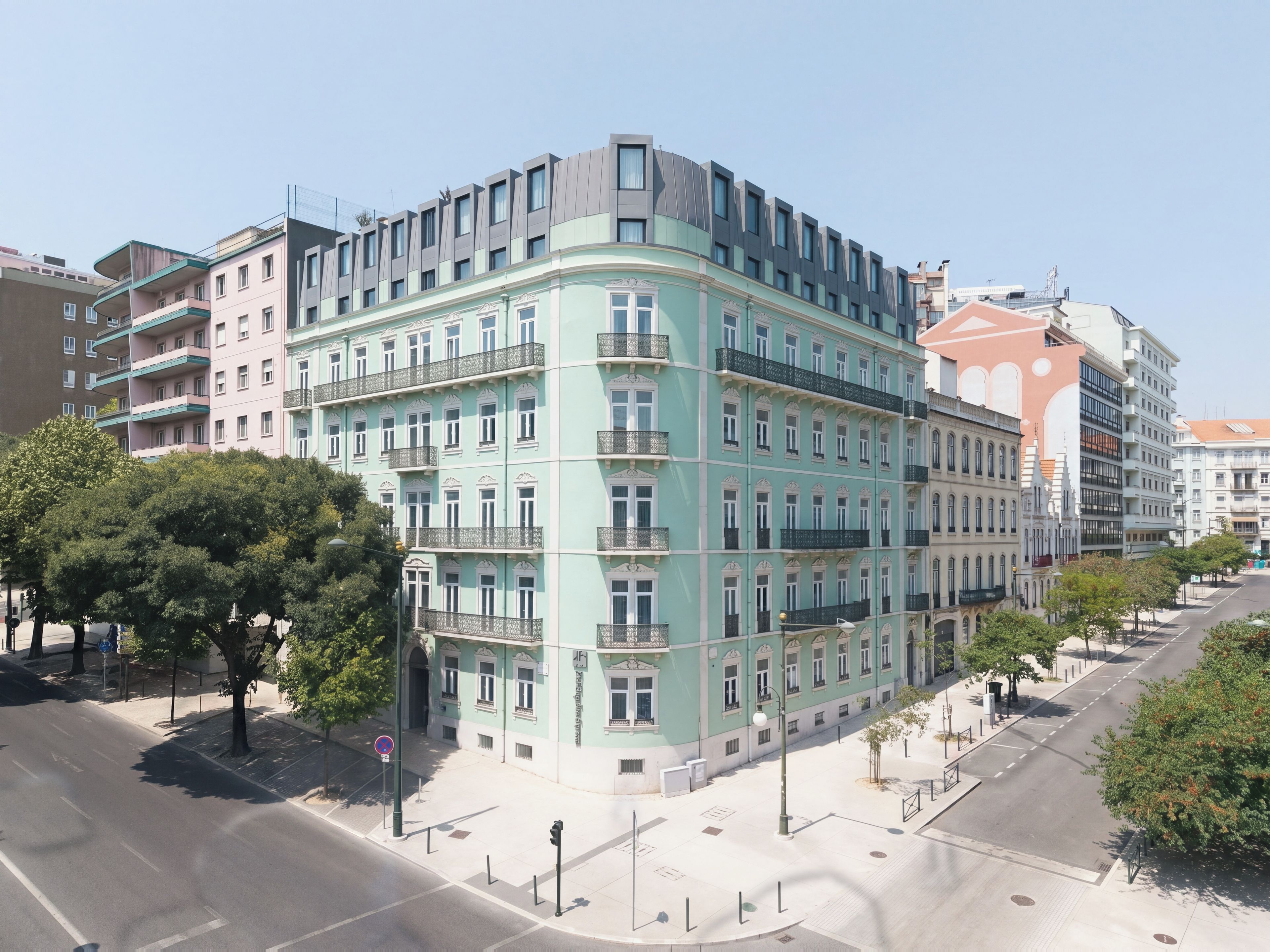A multi-story building with a curved facade, balconies, and a street view with trees and a clear sky.