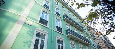 Um edifício de vários andares com fachada verde, várias janelas e varandas.