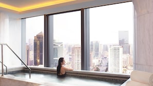 A spa area with a large window offering a city view, a marble bathtub, and a towel rack. - The Ritz-Carlton, Chengdu (Chengdu)