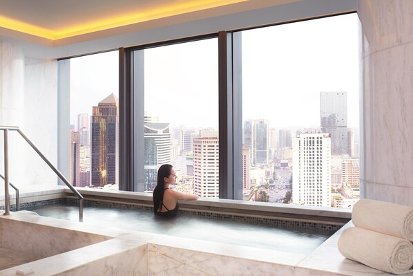 A spa area with a large window offering a city view, a marble bathtub, and a towel rack. - The Ritz-Carlton, Chengdu (Chengdu)