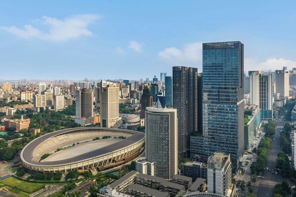 A cityscape with modern high-rise buildings, a large stadium, and a mix of residential and commercial structures.