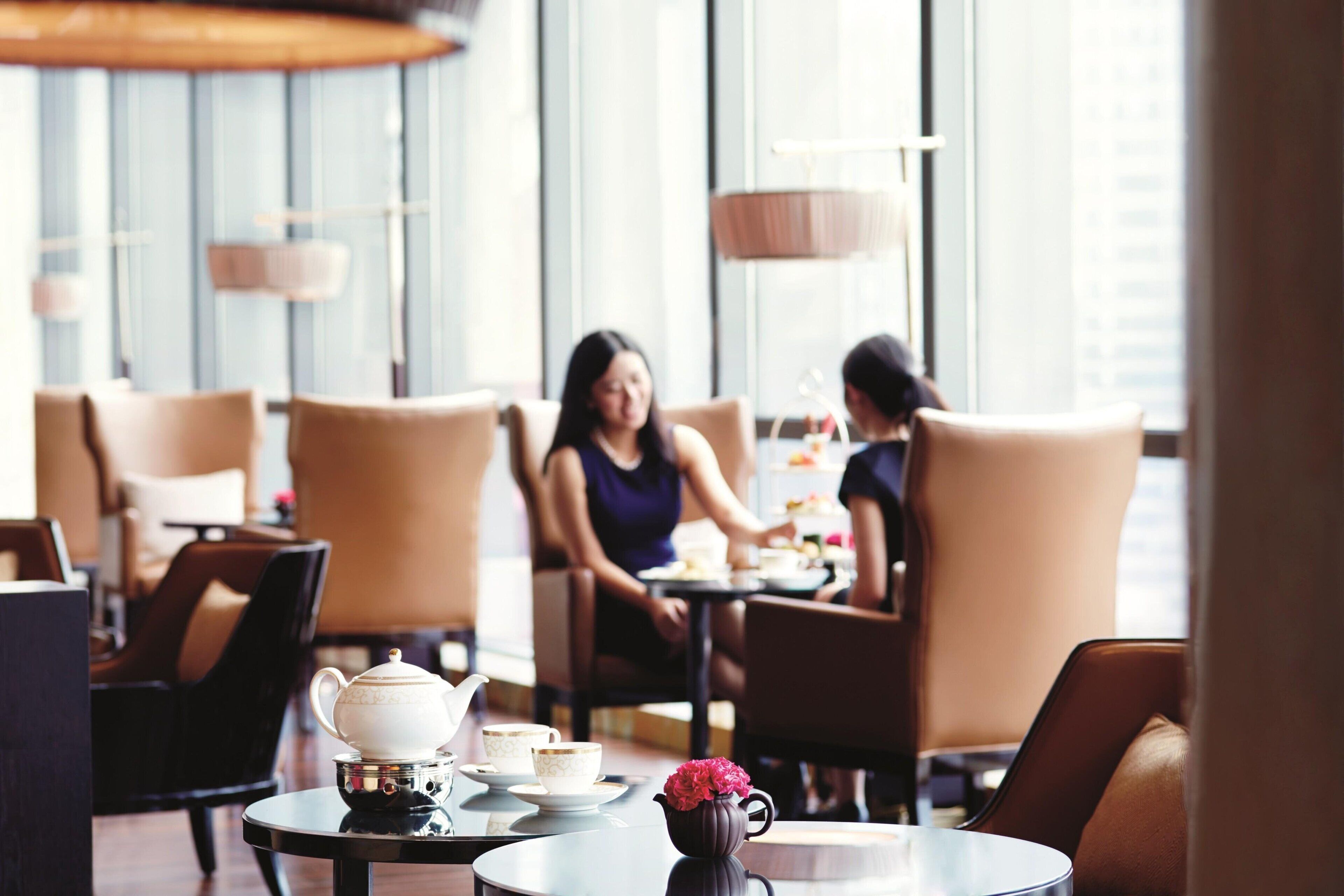 A cafe with round tables, chairs, and a teapot on one table.